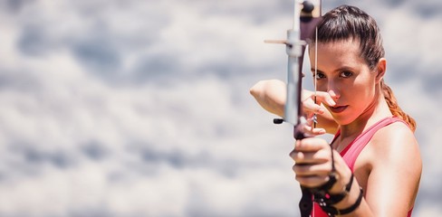Composite image of portrait of sportswoman practising archery 