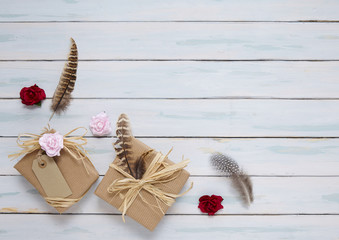 Gift wrap - Presents wrapped in brown parcel paper with raffia bows, blank tag, feathers, and red...