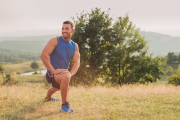 Attractive athletic man in his 30s stretching his legs outdoor preparing for exercise