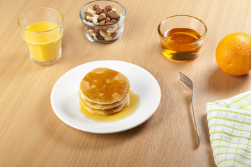 Plate of pancakes with a bowl of nuts on table