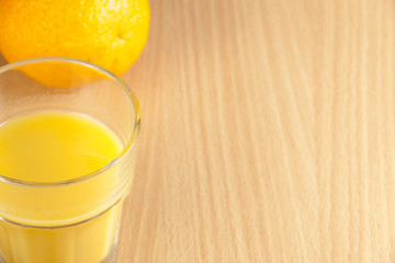 Whole orange and a glass of juice on breakfast table