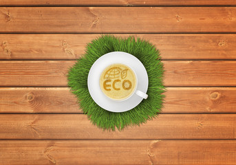 Cup of cappuccino coffee with image ECO symbol on wooden surface.