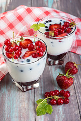 Yogurt dessert with  jelly and fresh red currant and strawberry on wooden table