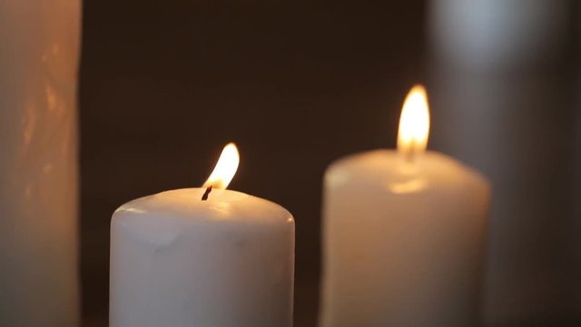 Pair of white wax candles shines brightly in dark room
