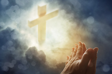Praying hands and cross in heavenly sky © Stillfx