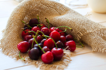 Fresh red cherries on wooden background with sacking napkin