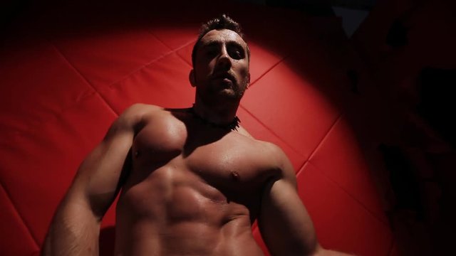 Brutal muscular man in the red room dancing. stripper handcuffed