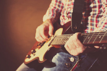 Young man playing on electric guitar