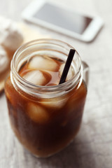Glass jar of iced coffee on wooden table