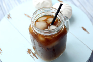 Glass jar of iced coffee on wooden table