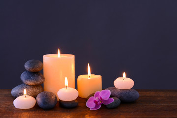 Fototapeta na wymiar Spa stones with burning candles and flower on grey background