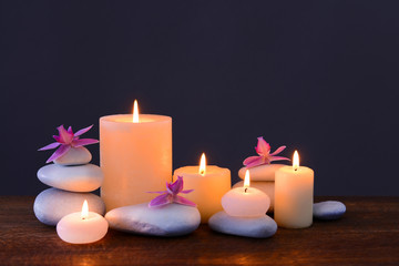 Fototapeta na wymiar Spa stones with burning candles and flowers on grey background