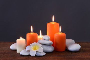 Spa stones with burning candles and flower on grey background