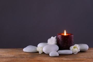 Fototapeta na wymiar Spa stones with burning candle and flowers on grey background