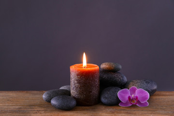 Obraz na płótnie Canvas Spa stones with burning candle and flower on grey background