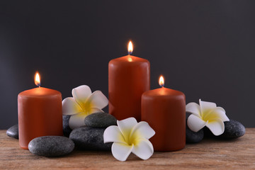 Obraz na płótnie Canvas Spa stones with burning candles and flowers on grey background