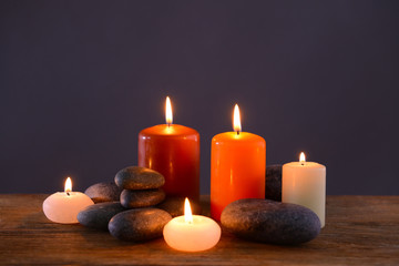 Fototapeta na wymiar Spa stones with burning candles on grey background
