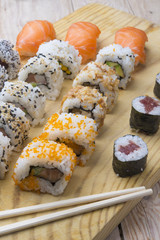 Different Sushi rolls,wasabi and ginger on a plate on wooden bac