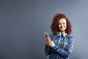 Attractive woman listening to music with headphones on grey background