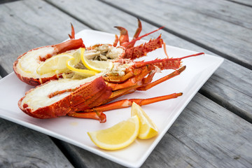 Cooked and halved New zealand crayfish on the wooden table. - obrazy, fototapety, plakaty