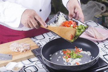 chef cooking onion, tomato and green bell pepper