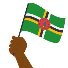 Hand holding and raising the national flag of Dominica