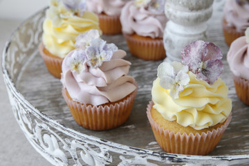 Purple and yellow cupcakes with sugared edible flowers on vintag