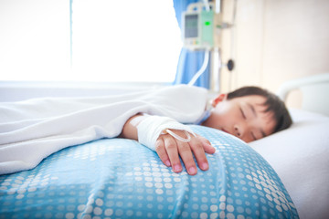 Obraz na płótnie Canvas Asian boy lying on sickbed with saline intravenous (IV). 