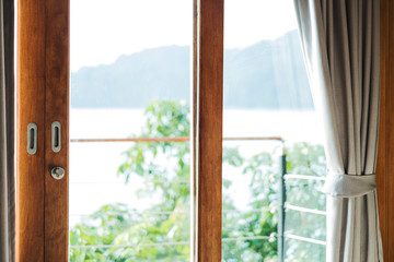 Wooden balcony door frame with curtain, in the morning