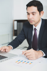 Handsome Asian businessman working in the office with laptop com