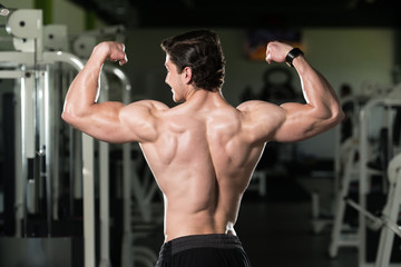 Fototapeta na wymiar Young Bodybuilder Flexing Rear Double Biceps Pose