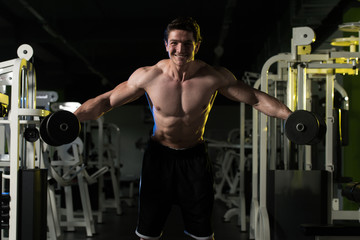 Young Man With Dumbbells Exercising Shoulders
