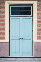A front entrance of a museum with a blue door and red brick siding