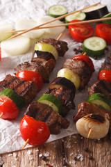 Tasty kebab with vegetables on skewers close-up. Vertical
