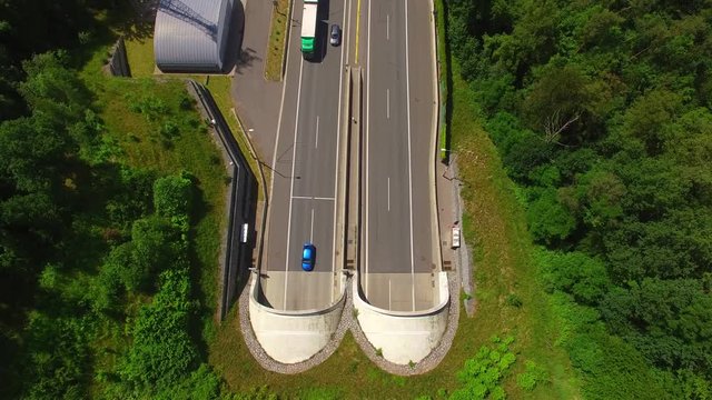 Aerial view of highway tunnel in mountains. Traffic on the road. Transportation from above. Industrial background.