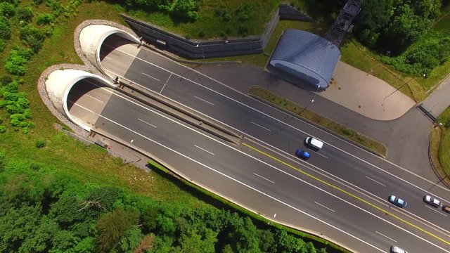 Aerial view of highway tunnel in mountains. Traffic on the road. Transportation from above. Industrial background.