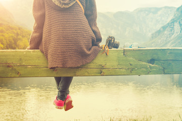 Girl sitting on a wooden pier near water.