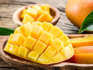 Mango fruit and mango cubes on the wooden table.