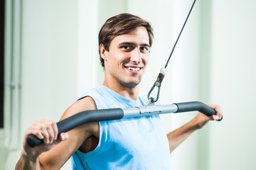 Happy man is exercising in gym.