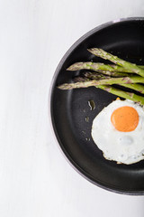 Green asparagus with fried egg on the frying pan
