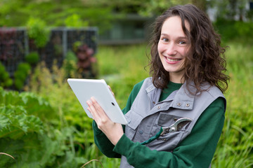 Fototapeta premium Young attractive woman working in a public garden using tablet