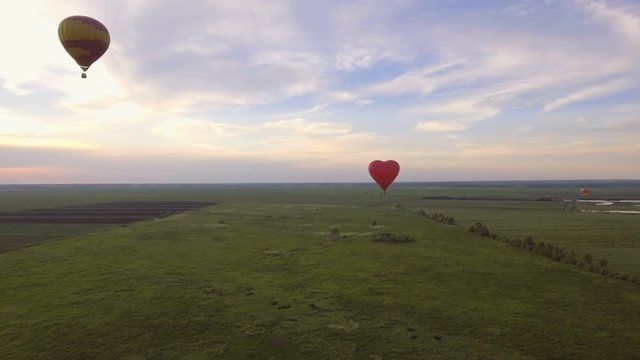 Hot air balloons in the sky over a field in the countryside.Aerial view:Hot air balloons in the sky over a field in the countryside in the beautiful sky and sunset.Aerostat fly in the countryside. 4K