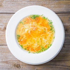 Chicken soup in white plate on wooden background