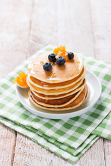 Homemade sweet pancakes with blueberries, fruit jam and honey on a white plate