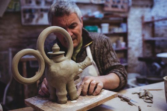 Mature male potter making clay elephant 