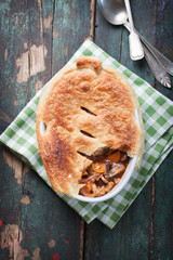 Homemade vegetable pie with tomato sauce and puff pastry in a bowl with red wine, top view .