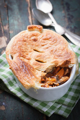 Homemade vegetable pie with tomato sauce and puff pastry in a bowl with red wine, top view