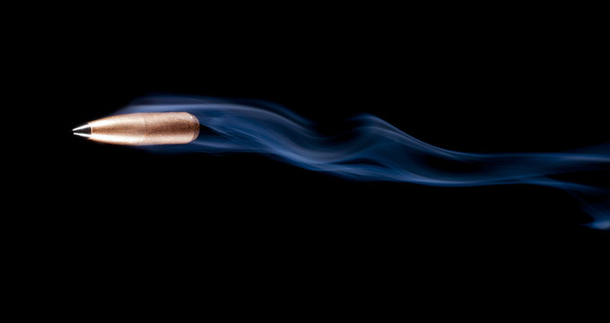 Bullet flying across a black background with smoke behind after a shooting