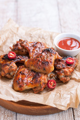 Roasted barbecue chicken wings with bbq sauce, italian herbs, olive oil and pepper, closeup