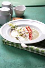 Zucchini cream soup with red pepper, cream, spices and balsamic cream on a wooden background